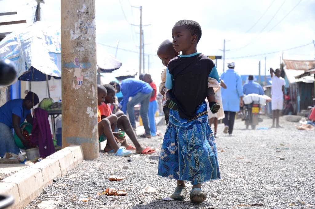 Ein Mädchen im Korogocho-Slum in Nairobi trägt ihre kleine Schwester auf dem Rücken. Photo © Lucas Oduor